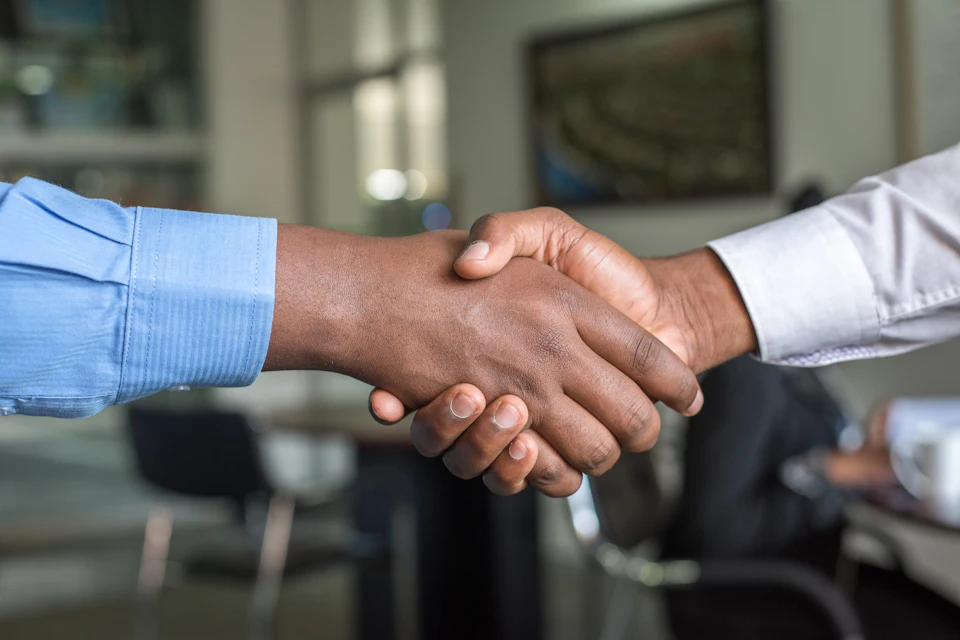 Two people shaking hands across a desk after a lending decision