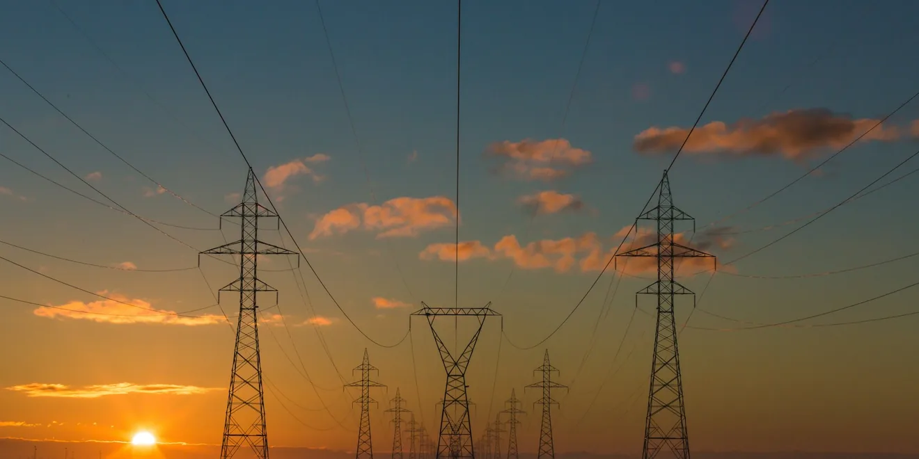 High-voltage transmission towers and power lines at dusk