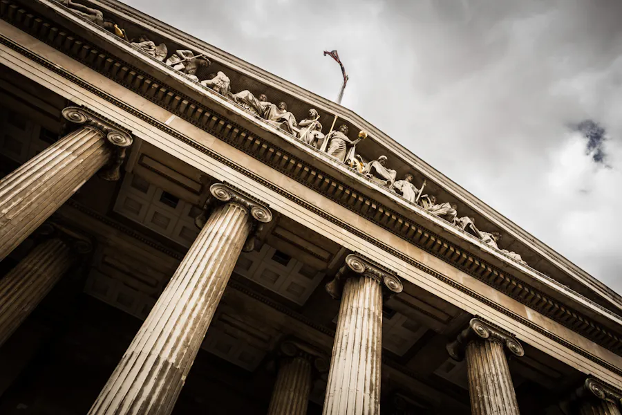 Classical columns of a courthouse against a dramatic sky